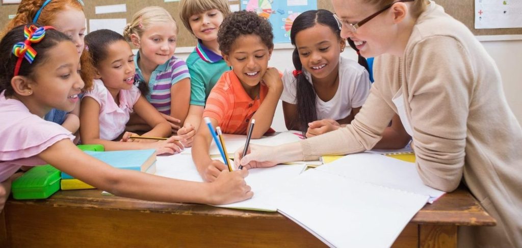 group-of-children-writing-with-teacher-min-copy-e1525423522257.jpg